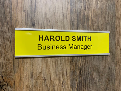 Yellow nameplate with 'Harold Smith, Business Manager' text on a wooden door.